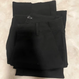 Svarta kostymbyxor i storlek 34 Bik Bok - Säljer ett par svarta kostymbyxor i klassisk rak modell. Byxorna har hällor för bälte och diskreta fickor framtill. Perfekta för en clean och stilren look. Materialet känns mjukt och följsamt, vilket gör dem bekväma att bära hela dagen.