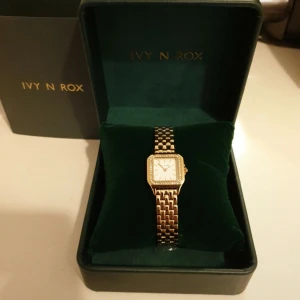 Ivy n Rox Posh klocka  - Helt ny och oanvänd Ivy N Rox Posh damklocka, fyrkantig, guld, 24x24 mm.   Färg band: Guld Glas: Mineralglas Material band: Rostfritt stål