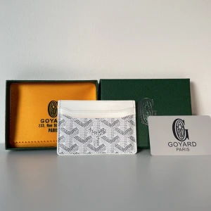 Vit plånbok från G yard - Supersnygg vit plånbok från G yard med klassiskt mönster i grått och svart. Slimmad design med flera fack för kort, perfekt att ha i fickan eller väskan. Kommer med original ask och dustbag. Lyxig vibe och riktigt stilren look.