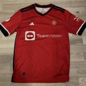 Manchester United Rashford 10 tröja säsong 23/24 helt ny - Säljer en officiell Manchester United matchtröja med Rashford och nummer 10 på ryggen. Tröjan är röd med svarta och vita detaljer, korta ärmar och Premier League-märke på ärmen. Adidas-logga och TeamViewer sponsor på framsidan. Tillverkad i lätt polyester.