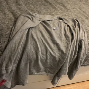 Grå kofta i mjuk bomull - Enkel och stilren grå kofta med lång ärm, perfekt att slänga på sig över en t-shirt. Mjuk och tunn i materialet, vilket gör den skön att bära under både höst och vår. Passar dig som gillar en clean och chill look.