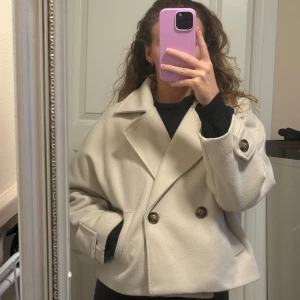 Beige jacka med stora knappar - Säljer en beige jacka från Missäy i kortare modell med bred krage och dubbelknäppning. OBS. Kan inte hitta storleken på jackan men skulle säga att den känns som en storlek M. Jackan har stora bruna knappar, två fickor framtill. 