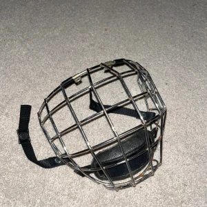 Jofa galler  - Säljer ett robust ishockeygaller i silverfärgad metall med svart hakskydd och justerbara svarta remmar. Perfekt för dig som vill skydda ansiktet på isen. Passar de flesta hjälmar och är lätt att montera.