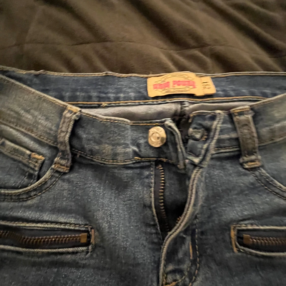 Blåa jeansbyxor med dragkedjedetaljer