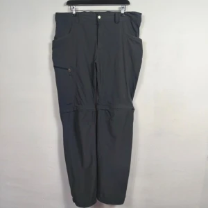 Svarta zip-off byxor från Haglöfs - Svarta friluftsbyxor från Haglöfs med zip-off-funktion så du kan göra om dem till shorts. Byxorna har dragkedja vid knäna, flera fickor inklusive en med dragkedja på sidan och bälteshällor. Perfekta för äventyr och outdoor.