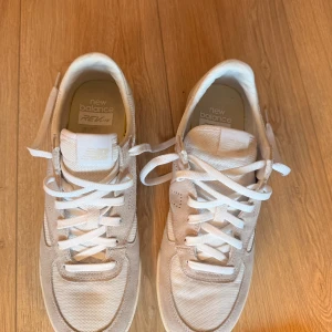 Vita New Balance sneakers REVlite - Snygga vita New Balance sneakers med REVlite-sula. Skorna har ovandel i mesh och mocka, vita snören och diskret logga på både plös och häl. Perfekta för dig som gillar stilrena och bekväma sneakers med klassisk vibe. endast provade, nya!