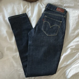 Levi's Bold Curve Skinny Jeans, mörkblå - Mörkblå Levi's Bold Curve skinny jeans med klassiska kontrastsömmar och femficksdesign. Snygg passform med låg midja och smala ben. Tillverkade i stretchig denim för extra komfort. Perfekta för dig som gillar en stilren och tidlös look.