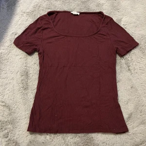 Vinröd ribbad topp från Amisu - Säljer en vinröd ribbad topp från Amisu i storlek M. Toppen har korta ärmar, rundad urringning och är figurnära i modellen. Perfekt att styla med jeans eller kjol för en snygg look. Tröjan är väldigt stretchig så passar S-L