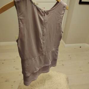 Ljuslila ärmlös blus från Stockh LM - Säljer en stilren ljuslila blus från Stockh LM i storlek 36. Blusen är ärmlös med rund halsringning och har en snygg lager-på-lager-effekt nedtill. Tillverkad i ett tunt, flowy material som ger en luftig känsla.