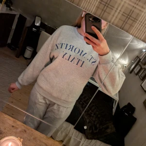 Grå sweatshirt St. Moritz Gina Tricot - Grå sweatshirt från Gina Tricot med blå text 'ST. MORITZ ITALY' framtill. Klassisk rund halsringning, ribbade muddar i storlek S. I bra sick