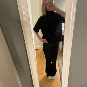 Svart stickad polotröja med kort ärm - Svart stickad polotröja med korta ärmar och loose passform. Tröjan har hög krage och är perfekt för lager-på-lager. Mjuk och skön, passar till både jeans och kjol. Enkel och stilren design som funkar året runt. I väldigt bra skick då den bara är använd två gånger.