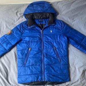 Polo Ralph Lauren jacka - Säljer en snygg Polo Ralph Lauren jacka perfekt för vinterkylan. Barnstorlek L 14-16. Jackan kommer i bra skick men har ett par små fläckar (se bild 3,4,5) Hör gärna av er vid minsta lilla fundering. 