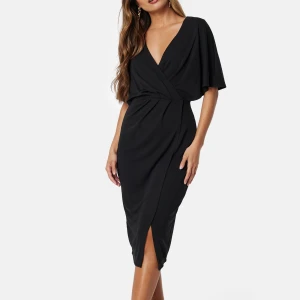 Svart klänning från Bubbleroom - Supersnygg helt oanvänd svart klänning från Bubbleroom med lappen kvar! V-ringning och korta, vida ärmar. Klänningen har en kort slits framtill och markerad midja som ger en smickrande siluett.🖤