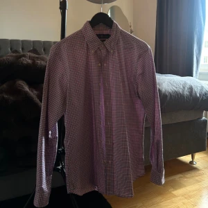 Rutig skjorta från Ralph Lauren M - Säljer en slim fit stretch oxfordskjorta från Ralph Lauren i storlek M. Skjortan har ett rutigt mönster i rosa, blått och vitt, klassisk krage och knäppning framtill. Perfekt för dig som gillar stilrena och färgglada skjortor.