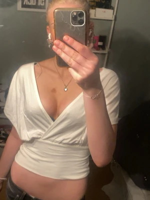 Vit omlottopp från lager 157 - Snygg vit omlottopp från lager 157 med djup v-ringning och bred midjeresår. Toppen har korta ärmar och knyt i ryggen. Perfekt att styla med jeans eller kjol för en trendig look.