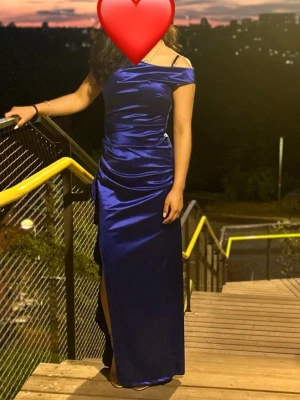 Marinblå axelbandslös långklänning/ Ballkläning  - Elegant marinblå långklänning i glansigt material med offshoulder-design och slits på sidan. Klänningen har en figurnära passform och är perfekt för speciella tillfällen. Snygg och stilren look som verkligen sticker ut.             Jag är 158 centimeter mina klackar hade typ 4 cm. 
