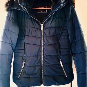Snygg mörkblå täckjacka från Havana!  - Snygg figursydd mörkblå pufferjacka med fickor fram och huva med fuskpäls från Havana i storlek 36/S. Nyskick!