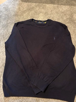 Mörkblå stickad tröja från Polo Ralph Lauren - Mörkblå stickad tröja från Polo Ralph Lauren. Säljer för att den är för liten. Nyskick inte blivit använd så mycket