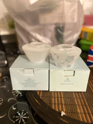 PartyLite mini lampskärmar i glas - Två PartyLite mini lampskärmar i frostat glas, en med blommönster i silver och en helt vit. Perfekta som dekoration till värmeljus eller små ljuslyktor. Säljes i originalkartong.