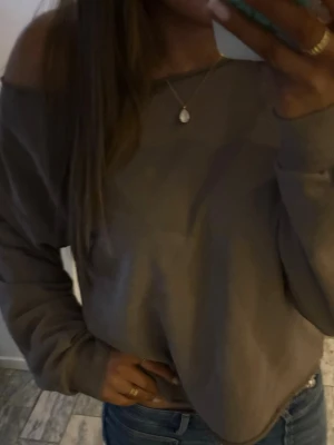 Brun off shoulder sweatshirt - Säljer en brun off shoulder sweatshirt med avslappnad passform och långa ärmar. Tröjan har bred mudd vid ärmslut och nederkant, perfekt för en chill och trendig look. Passar till jeans eller leggings för en casual stil.