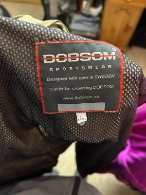 Beige funktionsväst från Dobsom XXXL - Beige funktionsväst från Dobsom i storlek XXXL. Västen har dragkedja framtill, flera praktiska fickor och meshfoder på insidan. Perfekt för dig som gillar sportig och avslappnad stil. Materialet är lätt och smidigt, vilket gör den enkel att bära.