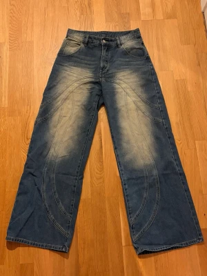 Blåa wide leg jeans med kontrastsömmar - Säljer ett par blåa wide leg jeans med mönster framtill. Använder tyvärr inte längre