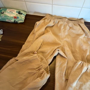 Beige lösa byxor  - Säljer ett par beige byxor med resår i midjan och vid bensluten. Byxorna har en avslappnad passform och är perfekta för chill dagar. Tillverkade i mjukt material som känns skönt mot huden.