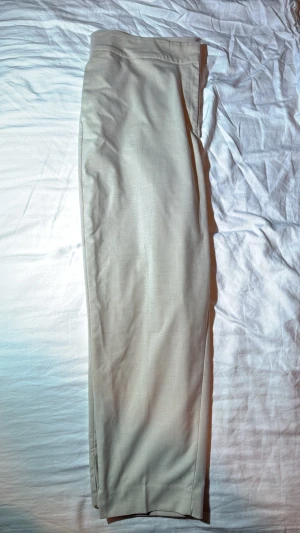 Beiga linnebyxor från H&M - Snygga beiga linnebyxor från H&M i storlek 46. Byxorna har en rak passform och är tillverkade i ett luftigt linnematerial som passar perfekt till varmare dagar. Stilrena och enkla att matcha med olika toppar för en avslappnad look.