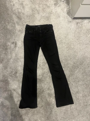 Svarta bootcut jeans från true religon  - Snygga svarta bootcut jeans från Replay med klassiska fickor fram och bak. Jeansen har mellan midja och är tillverkade i ett mjukt jeansmaterial. Perfekta för dig som gillar en tidlös och trendig look.