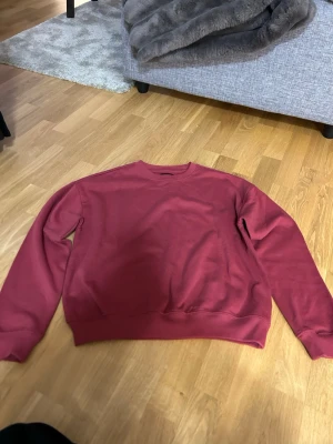 Vinröd sweatshirt - En enkel och snygg mörkröd sweatshirt med rund halsringning och ribbade muddar vid ärmar och nederkant. Den är i storlek XS och oanvänd.