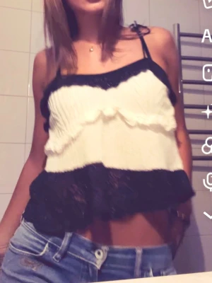 Svartvit croppad linnetopp - Säljer en croppad linnetopp i svart och vitt med volangdetaljer och tunna axelband. Toppen har en luftig passform och är perfekt för varma dagar. Supersnygg att matcha med jeans eller kjol!