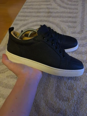 Loubs  - Säljer ett par svarta sneakers från Christian Louboutin i exklusivt präglat skinn. Box medföljer! Skicka ett pm för frågor elr annat! Vänster sko har ett smart märke på sulan! Går att få bort med tvätt!