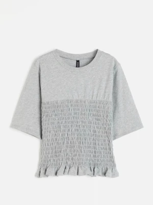 Grå topp med smock och volang - Snygg grå topp med smockad front och volangkant nedtill. T-shirten har rund halsringning och halvlånga ärmar. Perfekt att styla med jeans eller kjol för en trendig look.💝🥹