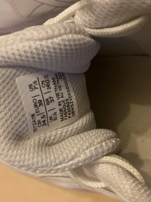 Vita sneakers från Asics - Säljer ett par fräscha vita sneakers från Asics med klassisk design. Skorna har snörning, meshpaneler för bra ventilation och detaljer i syntetmaterial. Perfekta för dig som gillar sportig stil och vill ha bekväma skor till vardags.