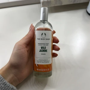 Wild Jasmine Fragrance Mist 100 ml - Fräsch och blommig doftmist från The Body Shop i doften Wild Jasmine. Flaskan är genomskinlig med silverfärgad spraykork och har en vit och orange etikett. Vegansk formula. Perfekt för dig som gillar lätta, blommiga dofter.