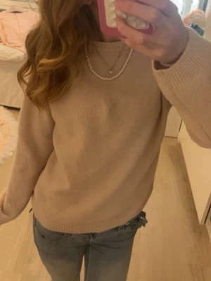 Ljusrosa stickad tröja - Mysig ljusrosa stickad tröja med rund hals och långa ärmar. Tröjan har ribbade muddar vid ärmslut och nederkant, och är tillverkad i ett mjukt material som passar perfekt till jeans. Enkel och stilren modell. Har dock två små fläckar som knappt syns.