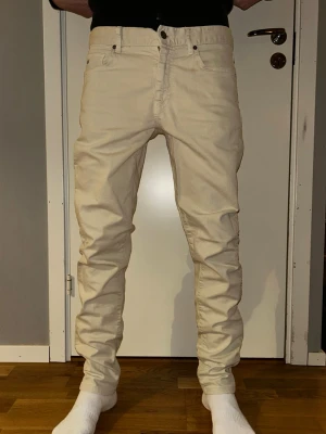 Beiga slim jeans i bomull - Snygga beiga jeans med slim passform och klassisk femficksdesign. Tillverkade i mjuk bomull som ger en skön känsla och stilren look. Perfekta för dig som vill ha ett par ljusa jeans med enkel och clean vibe. 32/34