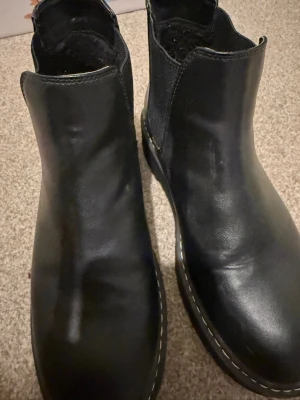 Svarta chelsea boots med platåsula - Svarta chelsea boots i skinn med rund tå och kraftig platåsula. Klassisk resår på sidorna och diskreta sömmar längs sulan. Perfekta för dig som vill ha en stilren men edgy look. 