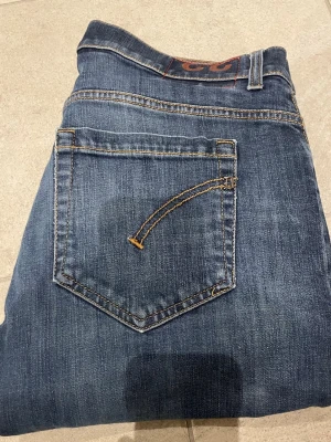 Blå jeans från dondup - Snygga blå jeans från dondup femficksmodell. Jeansen har en smal passform och raka ben, med diskreta slitningar och kontrastsömmar. Perfekta för dig som gillar en enkel men stilren look. Jeans är passar 33 32 31 i midjan