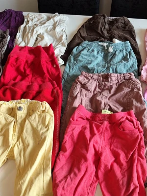 Färgglada byxor och shorts i bomull stl 74/80 - Säljer ett gäng färgglada byxor och shorts i olika modeller och färger, bland annat röd, gul, brun, rosa, blå och mönstrade. Perfekta för dig som gillar variation och bekväma material. Alla plagg är i mjuk bomull och har elastisk midja eller knapp.