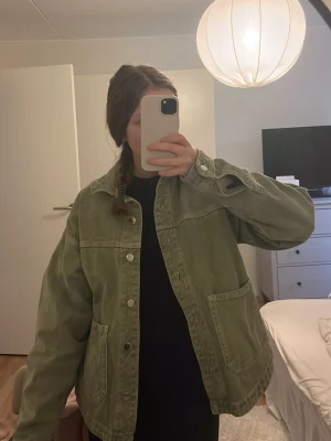 Grön jeansjacka från Zara - Snygg grön jeansjacka från Zara med klassisk krage, stora fickor framtill och knäppning med silvriga knappar. Jackan har en loose passform och är perfekt att slänga över en hoodie eller t-shirt för en chill look.