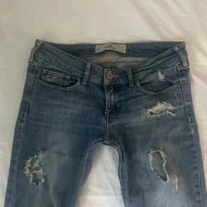 Hollister jeans - Jätte snygga omsydda lågmidjade jeans från Hollister! De är förstärkta, de bild, och omsydda vid benen! Storlek: W27 L31. Skriv om ni vill ha fler eller tydligare bilder på det omsydda eller förstärkta! Midjemått: ca 38cm Innerbenslängd: ca 73cm! 💕 priset kan diskuteras!