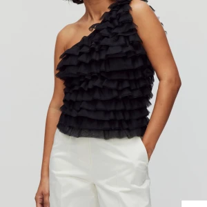 Svart oneshoulder topp med volanger - Säljer en superfin svart oneshoulder topp med massor av volanger. Perfekt för festliga tillfällen! Den är i ett mjukt och bekvämt material som sitter snyggt på kroppen. Orginalpriset ör 500. Andvänd några gånger 