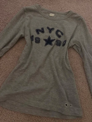 Långärmad tröja med nyc ”tryck” - Långärmad tröja från Urban outfitters bdg i storlek S💗Den är grå med ”på sytt” nyc logga, stjärna och sifffor. Använd ett fåtal gånger, så gott som ny!!