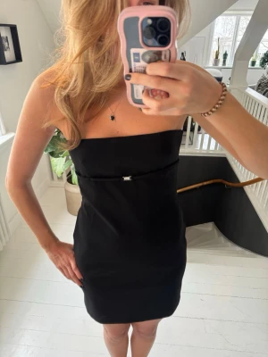 ZARA svart mini klänning med spännen i ryggen – storlek M - Skit snygg svart mini klänning från Zara i storlek M. Figurnära passform och supercoola detaljer i ryggen med spännen som verkligen gör klänningen unik  Perfekt för utekväll, fest, party eller date night. Tidlös men edgy – funkar året runt.  I mycket fint skick. Säljes pga kommer tyvärr inte till användning.