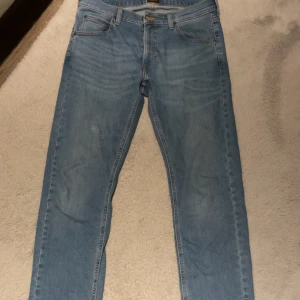 Ljusblå jeans från Levi's 511 - Säljer ett par ljusblå Levi's 511 jeans med klassisk femficksdesign och raka ben. Jeansen har en snygg tvätt och är tillverkade i mjukt denimtyg som sitter skönt. Perfekt för dig som gillar en stilren och avslappnad look.