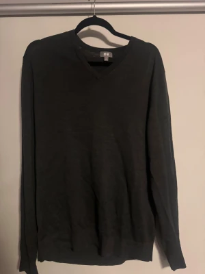 Mörkgrön v-ringad tröja från Uniqlo - En stilren mörkgrön v-ringad tröja från Uniqlo i storlek L. Tröjan har lång ärm och är tillverkad i mjuk ull som känns skön mot huden. Perfekt för dig som gillar enkel och clean look med en klassisk passform.
