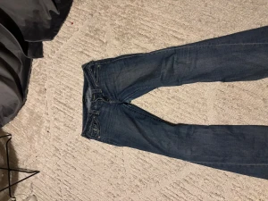 True Religion blå jeans med broderade fickor - Säljer ett par snygga blå jeans från True Religion med ikoniska broderade bakfickor och silverfärgade. Rätt så bra skick 