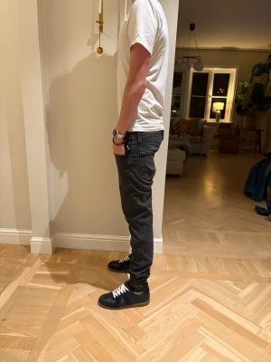 Svarta replay Anbass jeans - Säljer ett par svarta jeans från Replay med slim passform och klassisk femficksdesign. Jeansen har en mörk tvätt, raka ben och snygga detaljer vid fickorna. Materialet är stretchigt jeans för extra komfort och rörelsefrihet.