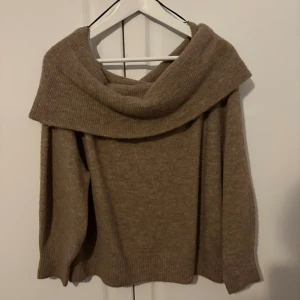 Beige offshoulder stickad tröja H&M - Säljer en beige stickad tröja från H&M i storlek M. Tröjan har en bred offshoulder-krage som ger en chill och snygg vibe. Materialet är mjukt och ribbstickat, perfekt för att hålla värmen under kyliga dagar. 